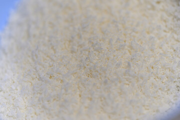 Shredded coconut close-up in a plastic blue bowl.
