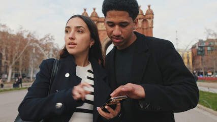 Two young people looking at smartphone together with blurred historical city background