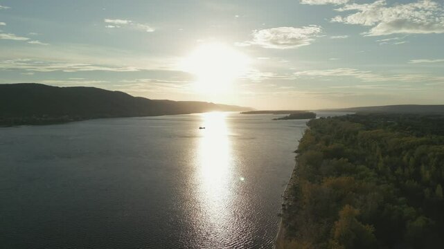 Sun setting over wide river and forest coastline