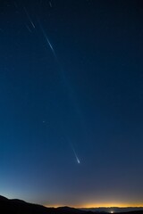 A bright meteor streaks across the night sky