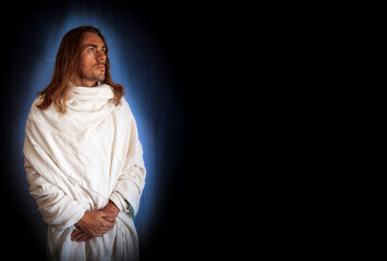 Handsome, religious, spiritual man in a white robe on a black background