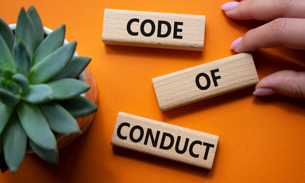 Code of conduct symbol. Wooden blocks with words Code of conduct. Businessman hand. Beautiful orange background with succulent plant. Business and Code of conduct concept. Copy space.