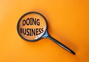 Doing Business symbol. Magnifying Glass with Concept word Doing Business. Beautiful orange background. Business and Doing Business concept. Copy space