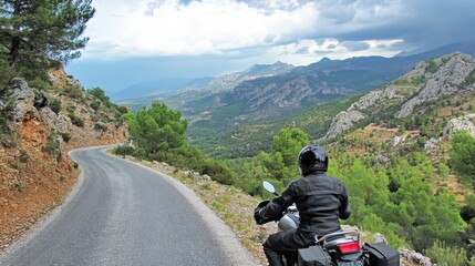 A motorcyclist riding up a winding mountain road, with stunning views of rugged terrain and lush greenery, wearing a full helmet and protective gear.