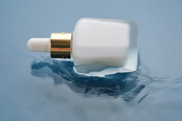 Bottle with white moisturizing serum in water on blue background.