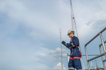 Engineer in Full Safety Gear Climbing a Ladder to Inspect Communication Signals and Industrial...