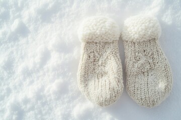 Cream-colored knitted mittens with fluffy pom-poms rest on a snowy surface.