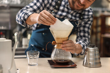 Barista making coffee with glass coffeemaker at table in cafe, closeup