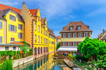 Old houses colorful facade, medieval buildings multicolored walls on bank of river Lauch canal with boats on water, old town Colmar city historic centre in summer day, Alsace Grand Est region, France