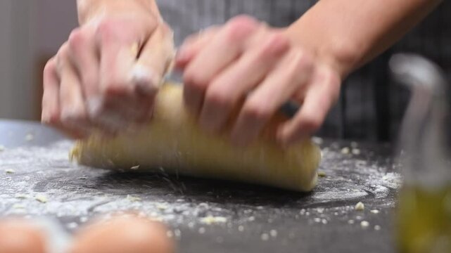Female hands kneading homemade dough in flour on the table, slow motion.
