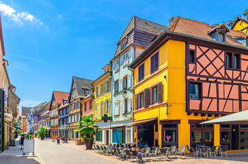 Fototapeta premium Old houses colorful facade, medieval buildings with colorful walls, shutters windows, street restaurant on pedestrian street in old town Colmar city historic centre, Alsace Grand Est region, France
