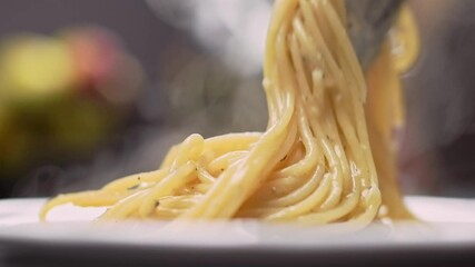Chef puts finished spaghetti pasta onto a plate.