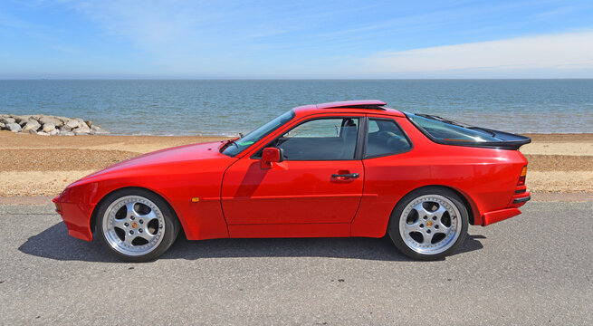 Classic Red   Porsche 944 Turbo Coup&eacute; parked on seafront promenade beach and sea in background