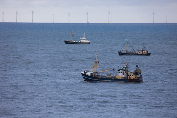 Three fishing vessels in front of an offshore wind park in the North sea near to Egmond aan Zee