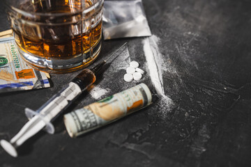 White narcotic pills, an alcoholic drink in a glass, a syringe with a dose of heroin, a line of...