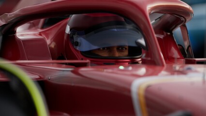 Close-up of a focused pilot driver in a red racing car, preparing for a race