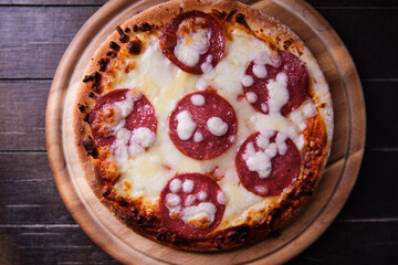 Pizza with salami and mozzarella cheese. Wooden background. Soft focus. Top view. Close up. 