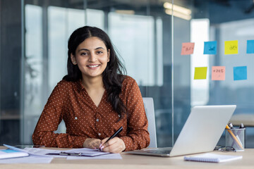 Portrait of a young successful businesswoman financier at her workplace inside the office....