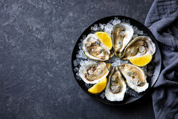 Fresh oysters with lemon on crushed ice. Dark background. Copy space. Top view.