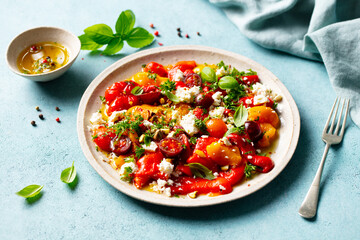 Roasted sweet pepper salad with cherry tomatoes and feta cheese. Blue background. Close up.