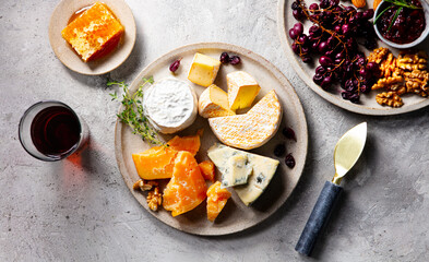 Cheese assortment on a plate with glass of red wine. Grey background. Close up. Top view.