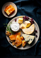 Cheese assortment on a grey plate. Dark background. Close up. Top view.