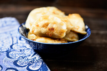Dumplings with potato and cottage cheese stuffing (pierogi). Wooden background. Close up.
