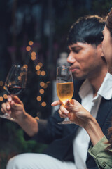 Intimate Wine Toast: A couple enjoying a romantic evening together, raising a glass of wine to celebrate a special occasion. The warm glow of the lights creates a cozy and intimate atmosphere.  