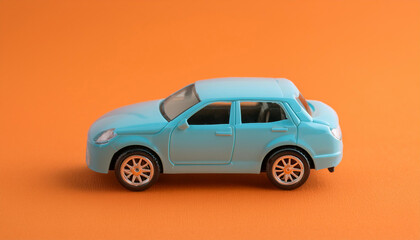 Fototapeta premium Blue children toy car isolated on orange backdrop. Vehicle insurance.