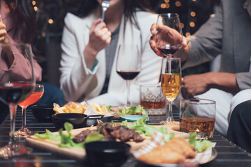 After-Work Drinks: A lively group of friends cheers with glasses of wine and beer, enjoying a casual dinner together, creating a warm and convivial atmosphere. 