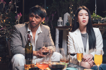 Couple Enjoying a Night Out: A man and a woman, dressed in elegant attire,  share a quiet moment of conversation and a glass of wine at a sophisticated gathering.