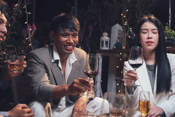 Nighttime Social Gathering: A group of friends and colleagues enjoy a relaxed and convivial evening together, sharing drinks and laughter in an intimate setting.