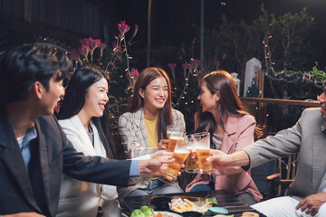 Nightlife Cheers: Friends toasting beers at an outdoor restaurant. A lively scene of young adults enjoying drinks and conversation under warm lighting.  