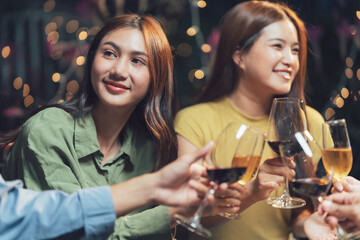 Cheers to Friendship: Two women, radiant with smiles, clink glasses of wine with friends, capturing the essence of camaraderie and celebration.