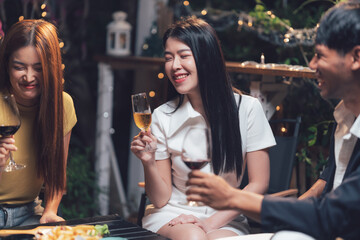 Nighttime Cheers: Friends enjoying drinks and conversation at a cozy outdoor gathering. Warm lighting and laughter fill the scene. 