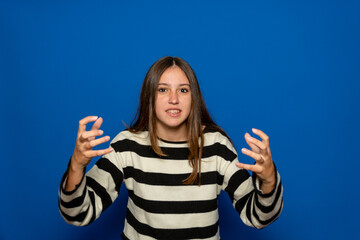 Beautiful hispanic teenage girl about 15 years old wearing a striped sweater with clapped hands in...