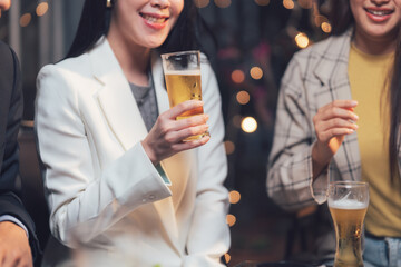 Cheers to Success: A group of young professionals celebrate a successful evening with drinks and laughter. The warm lighting creates a cozy and inviting atmosphere.