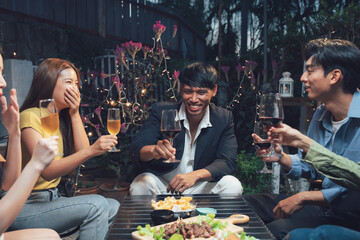 Nighttime Gathering: A group of friends gather around a table, sharing laughter, drinks, and good times under the warm glow of evening lights. The scene captures the essence of friendship, connection.