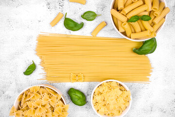 Minimalistic culinary composition with pasta of different shapes on a light textured background....