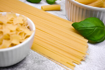 Minimalistic culinary composition with pasta of different shapes on a light textured background....