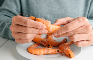 closeup of a man removing the head of a prawn
