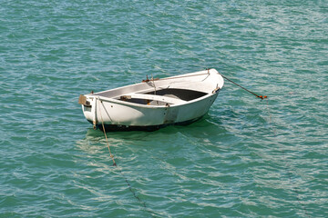 An old, white rowing boat anchored in the sea of the Bay of Fairy Tales, Sestri Levante, Genoa, Liguria, Italy