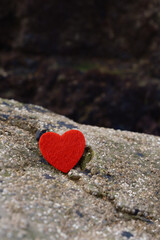 Fototapeta premium Red heart on a textured rock surface outdoors