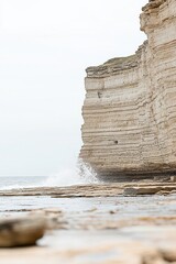 Dramatic coastal scene of layered rock cliffs with crashing waves, showcasing the power of nature's...