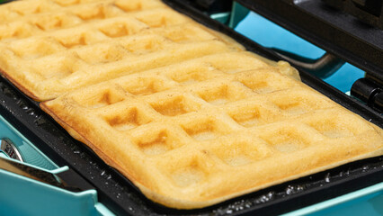 Delicious homemade classic waffle with non-stick coated waffle maker. Fluffy waffle batter, close-up view.