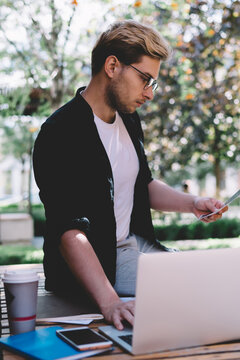 Adult dedicated employee revising reports and interacting with laptop on street in city