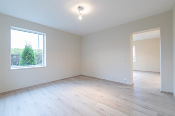 Modern New Construction Empty Room With Wooden Flooring and Large Windows Allowing Natural Light. Home Interior