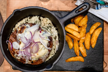 Onion Burger. Meat burger of ground meat fried in oil on a frying pan with three types of onions, close up