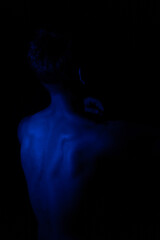 Junger Mann aus Indien steht mit freiem Oberk&ouml;rper in buntem Licht und posiert