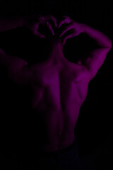 Junger Mann aus Indien steht mit freiem Oberk&ouml;rper in buntem Licht und posiert